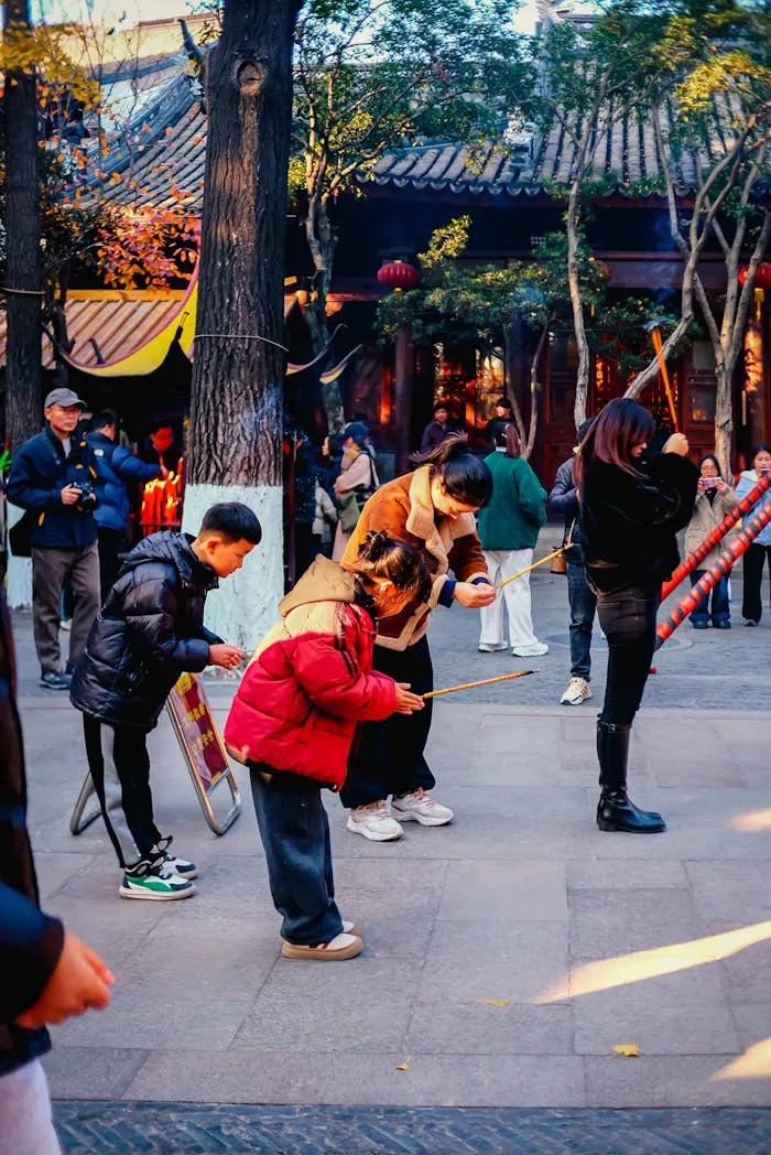 A group of people lighting incense sticks during a temple ceremony outdoors.