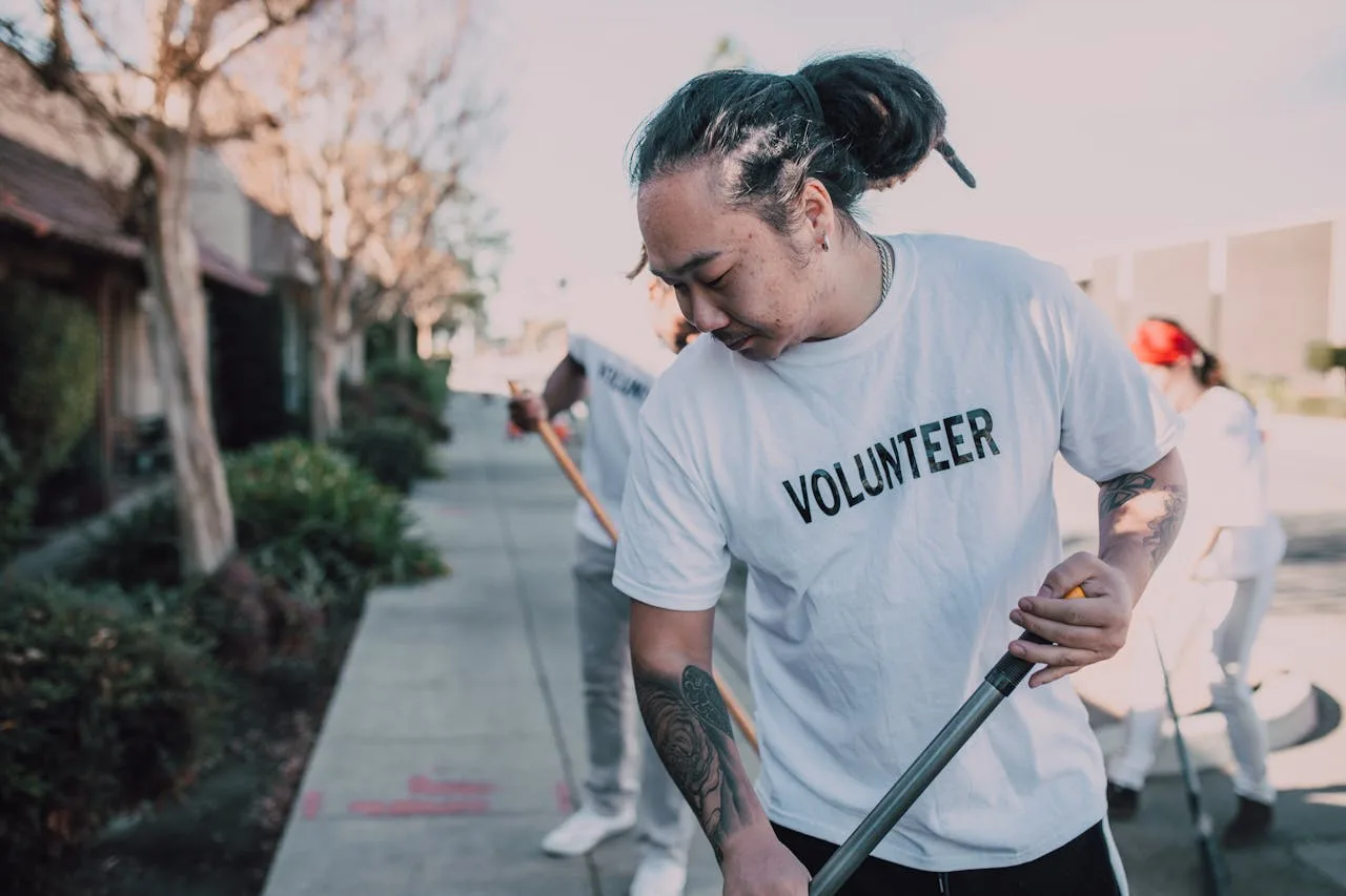 Volunteers in white shirts clean a city sidewalk, promoting community spirit and teamwork.