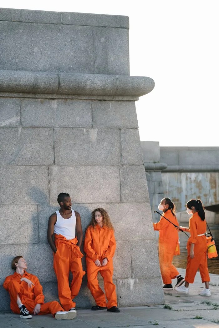 Group of diverse individuals in orange uniforms engaging in community service outdoors.